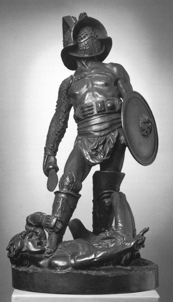 A bronze sculpture of a man in a gladiator uniform of a face covering helmet, large belt, loin cloth, gauntlets, round shield, and shin guards stands on the neck of a writhing man also dressed as a gladiator