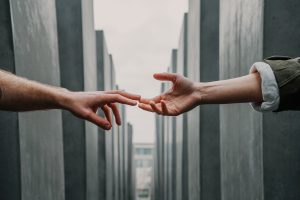 two hands touching between buildings.