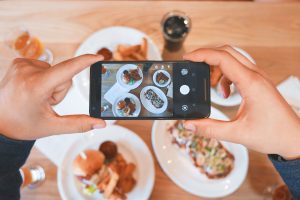 a person taking a picture with their iphone of food dishes