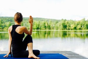 a lady doing yoga beside a lake