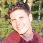 young man with short light brown hair smiling and wearing a read hoodie