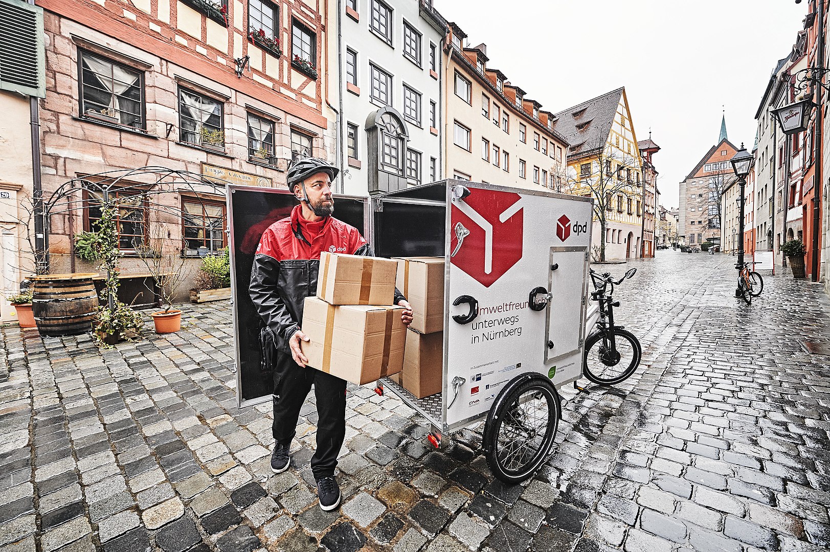 a guy delivering packages with a bike and little covered wagon behind it