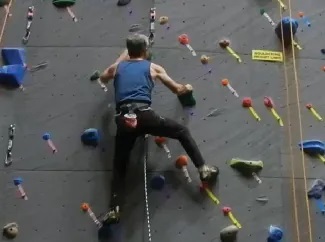 A picture shows a person in a harness ascending a climbing wall.