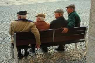 Four people are sitting on a bench looking off in the same direction.