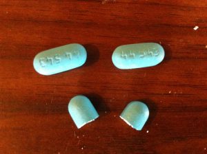 Three blue cold and allergy caplets with one broken in half