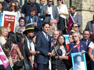 Descriptive image showing Justin Trudeau speaking to a mixed crowd outdoors about missing and murdered indigenous women.