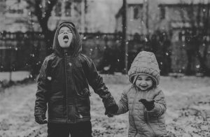 A photograph shows two children happily catching snowflakes.