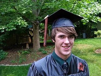 A photo shows a smiling person wearing a graduation cap and gown
