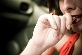 A photograph shows a woman biting her fingernails.
