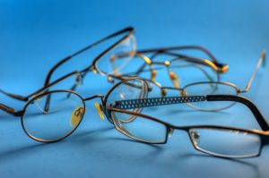 Multiple eyeglasses scattered on a blue background.