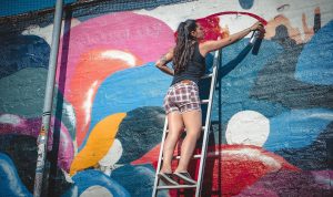 a lady spraying with spray paint on a wall