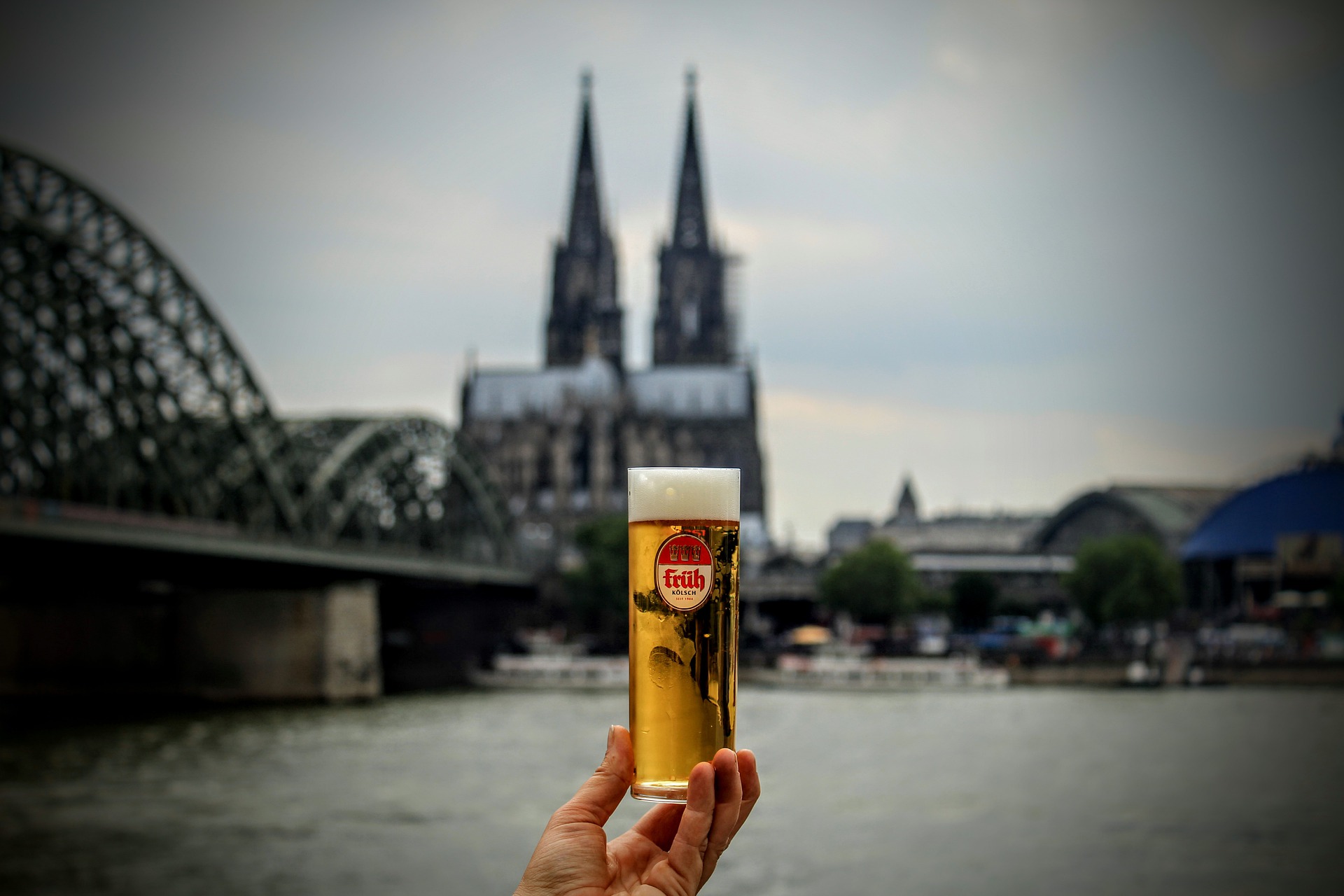 someone holding up a glass of "Kölsch" in Köln